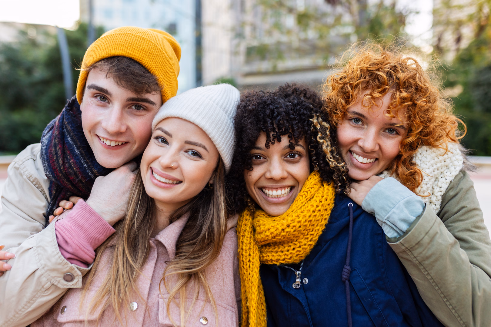 Vier lächelnde junge Freunde draußen in warmer Winterkleidung