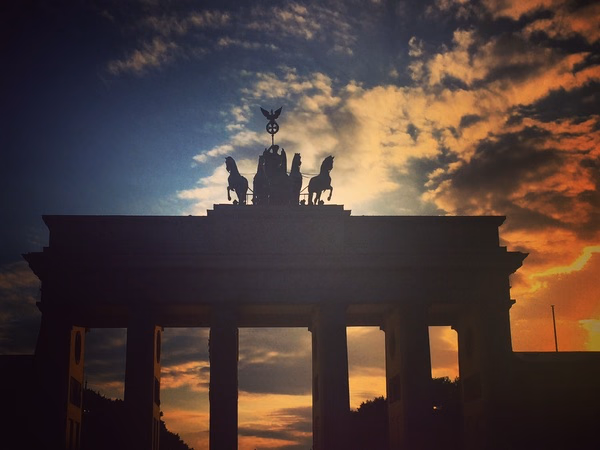 Brandenburger Tor in Berlin als dunkle Silhouette vor einem dramatischen Sonnenuntergang