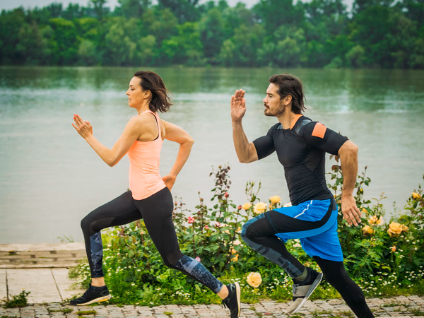 Zwei Läuferinnen und Läufer joggen am Seeufer entlang