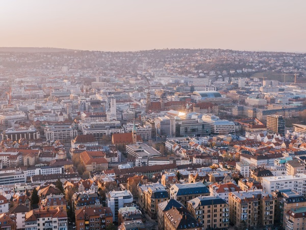 Luftaufnahme von Stuttgart mit dicht bebauter Innenstadt und hügeliger Wohnbebauung im Abendlicht